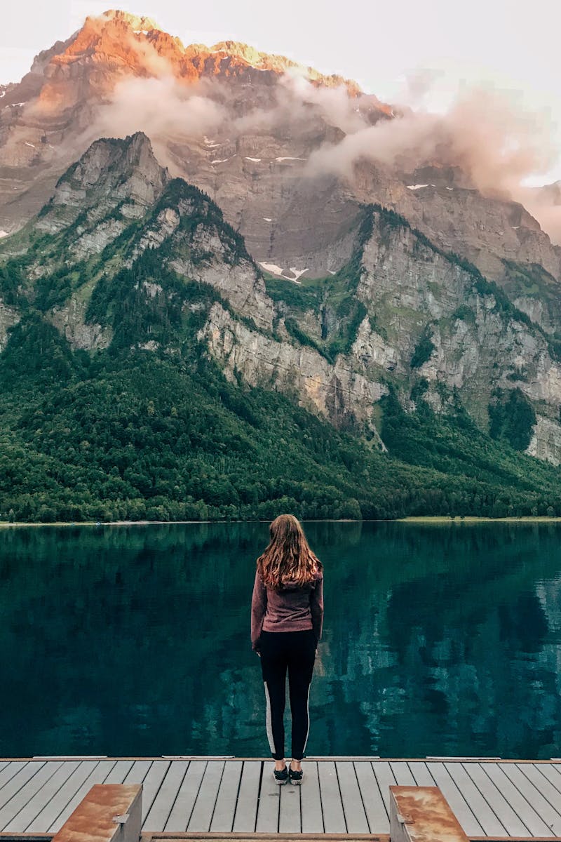 Woman standing at Klöntalersee in Switzerland with scenic mountain background.